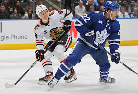 TORONTO, CANADA – OCTOBER 16: Connor Bedard #98 of the Chicago Blackhawks sneeks behind Jake McCabe #22 of the Toronto Maple Leafs   (Photo by Claus Andersen/Getty Images)