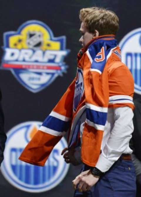 Jun 26, 2015; Sunrise, FL, USA; Connor McDavid puts on a team jersey after being selected as the number one overall pick to the Edmonton Oilers in the first round of the 2015 NHL Draft at BB&T Center. Mandatory Credit: Steve Mitchell-USA TODAY Sports