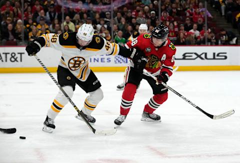 Mar 15, 2022; Chicago, Illinois, USA; Boston Bruins defenseman Matt Grzelcyk (48) knocks the puck away from Chicago Blackhawks right wing Patrick Kane (88) during the first period at the United Center. Mandatory Credit: Mike Dinovo-USA TODAY Sports