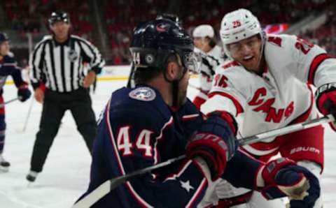 Oct 3, 2022; Raleigh, North Carolina, USA; Columbus Blue Jackets defenseman Erik Gudbranson (44) battles against Carolina Hurricanes right wing Stelio Mattheos (49) and defenseman Ethan Bear (25) during the second period at PNC Arena. Mandatory Credit: James Guillory-USA TODAY Sports