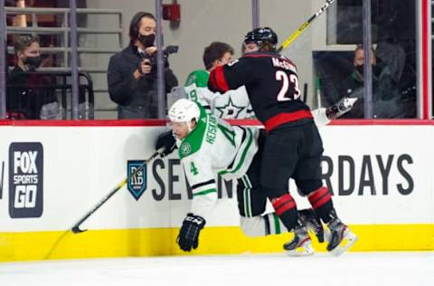 Jan 30, 2021; Raleigh, North Carolina, USA; Carolina Hurricanes left wing Brock McGinn (23) checks Dallas Stars defenseman Miro Heiskanen (4) during the first period at PNC Arena. Mandatory Credit: James Guillory-USA TODAY Sports