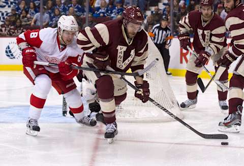 VANCOUVER, CANADA – MARCH 16: Andrew Ebbett #25 of the Vancouver Canucks tries to clear the puck while being checked by Justin Abdelkader #8 of the Detroit Red Wings during the third period of NHL action on March 16, 2013 at Rogers Arena in Vancouver, British Columbia, Canada. (Photo by Rich Lam/Getty Images)