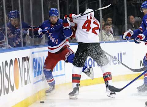 Curtis Lazar of New Jersey Devils hits Alexis Lafreniere of New York Rangers. (Photo by Bruce Bennett/Getty Images)