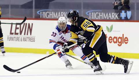 Jan 22, 2021; Pittsburgh, Pennsylvania, USA; Pittsburgh Penguins defenseman Kris Letang (58) skates with the puck as New York Rangers left wing Phillip Di Giuseppe (33) defends during the second period at the PPG Paints Arena. Pittsburgh won 4-3 in a shoot-out. Mandatory Credit: Charles LeClaire-USA TODAY Sports