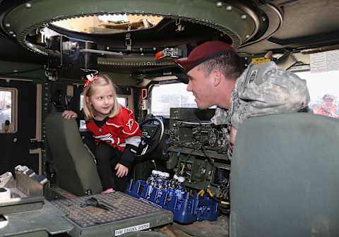 RALEIGH, NC – MARCH 08: A soldier describes the workings of an armored humvee to a young fan on Military Appreciation Day prior to an NHL game between the Carolina Hurricanes and the Edmonton Oilers at PNC Arena on March 8, 2015 in Raleigh, North Carolina. (Photo by Gregg Forwerck/NHLI via Getty Images)