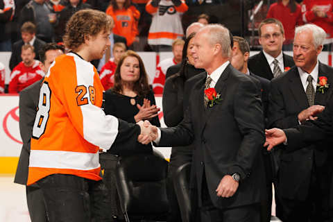 Flyers legend Mark Howe shakes hands with Claude Giroux during a ceremony retiring his number. (Photo by Rob Carr/Getty Images)