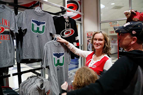 Carolina Hurricanes fans Jennifer Miller, left, and her husband Lawrence Miller, right, and their daughter Avery Miller, 9, check out the Hartford Whalers shirts for sale at The Eye before the Hurricanes play host to the Montreal Canadiens at PNC Arena in Raleigh, N.C., on Thursday, Feb. 1, 2018. It’s the first time items from the team’s former identity are being sold, a change brought about by the Canes’ new owner, Tom Dundon. (Chris Seward/Raleigh News & Observer/TNS via Getty Images)