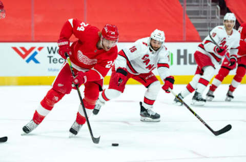 Jan 16, 2021; Detroit, Michigan, USA; Detroit Red Wings defenseman Jon Merrill (24) and Carolina Hurricanes center Vincent Trocheck (16) at Little Caesars Arena. Mandatory Credit: Eric Bronson-USA TODAY Sports