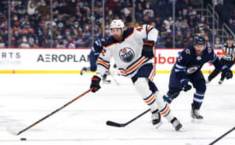 Feb 19, 2022; Winnipeg, Manitoba, CAN; Edmonton Oilers left wing Brendan Perlini (42) skates past Winnipeg Jets center Jansen Harkins (12) in the first periodat Canada Life Centre. Mandatory Credit: James Carey Lauder-USA TODAY Sports