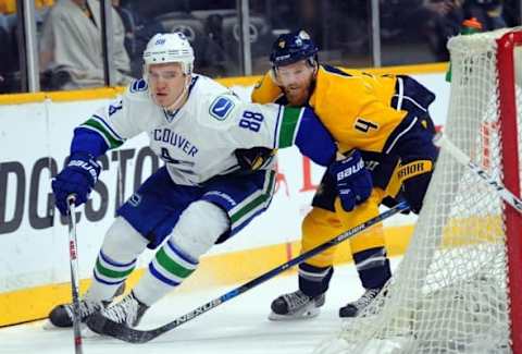 Mar 24, 2016; Nashville, TN, USA; Vancouver Canucks defenseman Nikita Tryamkin (88) skates with the puck behind the net while chased by Nashville Predators defenseman Ryan Ellis (4) during the second period at Bridgestone Arena. Mandatory Credit: Christopher Hanewinckel-USA TODAY Sports