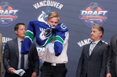 Jun 24, 2016; Buffalo, NY, USA; Olli Juolevi puts on a team jersey after being selected as the number five overall draft pick by the Vancouver Canucks in the first round of the 2016 NHL Draft at the First Niagra Center. Mandatory Credit: Timothy T. Ludwig-USA TODAY Sports