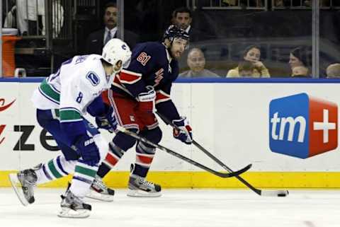 Nov 30, 2013; New York, NY, USA; New York Rangers left wing Rick Nash (61) looks to pass defended by Vancouver Canucks defenseman Chris Tanev (8) during the second period at Madison Square Garden. Mandatory Credit: Adam Hunger-USA TODAY Sports