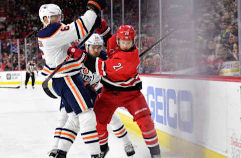 RALEIGH, NORTH CAROLINA – FEBRUARY 16: Sebastian Aho #20 of the Carolina Hurricanes battles Marcus Granlund #60 and Leon Draisaitl #29 of the Edmonton Oilers for the puck during the first period of their game at PNC Arena on February 16, 2020 in Raleigh, North Carolina. (Photo by Grant Halverson/Getty Images)