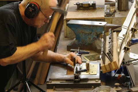 Artisan Michael Friedrichs-Friedlaender hammers inscriptions into the brass plaques at the Stolpersteine manufacturing studio in Berlin.