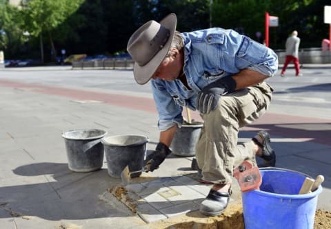 Artist Gunter Demnig lays a Stolpersteine outside a residence in Hamburg, Germany in 2012.