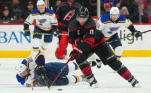 Feb 21, 2023; Raleigh, North Carolina, USA; Carolina Hurricanes center Jordan Staal (11) gets the puck away from St. Louis Blues center Jordan Kyrou (25) during the third period at PNC Arena. Mandatory Credit: James Guillory-USA TODAY Sports