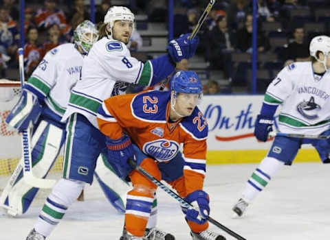 Mar 18, 2016; Edmonton, Alberta, CAN; Edmonton Oilers forward Matt Hendricks (23) and Vancouver Canucks defensemen Chris Tanev (8) battle in front of the Vancouver Canucks net during the first period at Rexall Place. Mandatory Credit: Perry Nelson-USA TODAY Sports