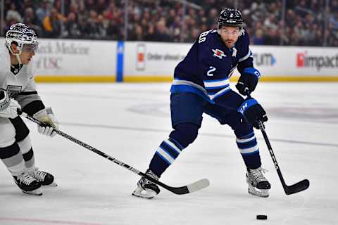 Mar 25, 2023; Los Angeles, California, USA; Winnipeg Jets defenseman Dylan DeMelo (2) moves the puck against Los Angeles Kings left wing Trevor Moore (12) during the first period at Crypto.com Arena. Mandatory Credit: Gary A. Vasquez-USA TODAY Sports