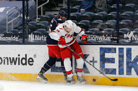 Mar 25, 2021; Columbus, Ohio, USA; Carolina Hurricanes left wing Warren Foegele (13) checks Columbus Blue Jackets defenseman Dean Kukan (46) during the second period at Nationwide Arena. Mandatory Credit: Russell LaBounty-USA TODAY Sports