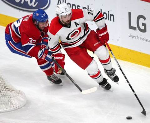 Feb 7, 2016; Montreal, Quebec, CAN; Carolina Hurricanes defenseman Justin Faulk (27) plays the puck against Montreal Canadiens right wing Brian Flynn (32) during the second period at Bell Centre. Mandatory Credit: Jean-Yves Ahern-USA TODAY Sports