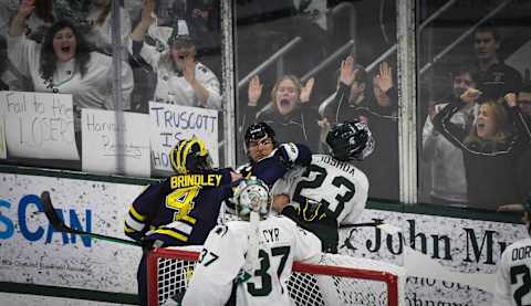 Gavin Brindley of U-M throws a punch at MSU’s Jagger Joshua as hockey fans cheer behind the glass, Friday, Feb. 10, 2023, at Munn Ice Arena. The Wolverines won 4-2.Dsc 2628