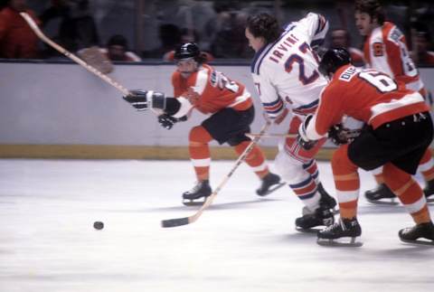 Ted Irvine (C) chased down by the Philadelphia Flyers’ Andre Dupont (R). (Photo by Melchior DiGiacomo/Getty Images)