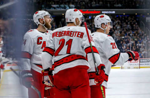 WINNIPEG, MB – DECEMBER 17: Jaccob Slavin #74, Nino Niederreiter #21 and Sebastian Aho #20 of the Carolina Hurricanes celebrate a second period goal against the Winnipeg Jets at the Bell MTS Place on December 17, 2019 in Winnipeg, Manitoba, Canada. (Photo by Jonathan Kozub/NHLI via Getty Images)