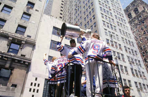 Hockey player Mark Messier of the New York Rangers holds the Stanley Cup aloft as he and his teammates celebrate their victory over the Vancouver Canucks earlier in the week with a ticker-tape parade in New York, New York, June 17, 1994. (Photo by Bruce Bennett Studios via Getty Images Studios/Getty Images)