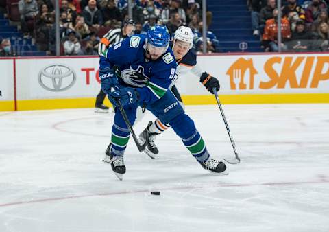 Oct 30, 2021; Vancouver, British Columbia, CAN; Vancouver Canucks forward J.T. Miller (9) moves the puck past Edmonton Oilers forward Jesse Puljujarvi (13) in the second period at Rogers Arena. Mandatory Credit: Bob Frid-USA TODAY Sports