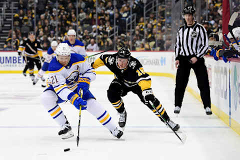 PITTSBURGH, PENNSYLVANIA – DECEMBER 17: Kyle Okposo #21 of the Buffalo Sabres controls the puck against Sam Lafferty #18 of the Pittsburgh Penguins during the first period of a game at PPG PAINTS Arena on December 17, 2021 in Pittsburgh, Pennsylvania. (Photo by Emilee Chinn/Getty Images)