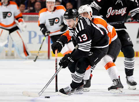 Nico Hischier shields the puck from the Flyers’ Morgan Frost. (Photo by Elsa/Getty Images)