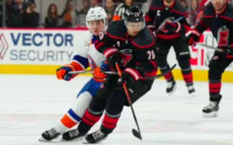 Apr 2, 2023; Raleigh, North Carolina, USA; Carolina Hurricanes center Sebastian Aho (20) and New York Islanders defenseman Sebastian Aho (25) battle over the puck during the third period at PNC Arena. Mandatory Credit: James Guillory-USA TODAY Sports