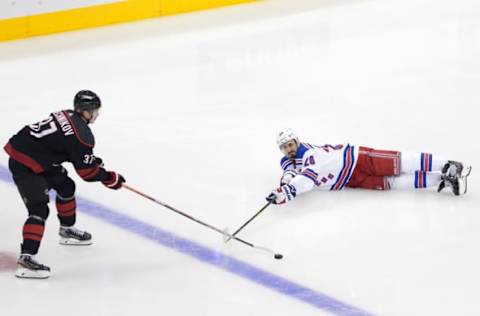 Chris Kreider #20 of the New York Rangers slides on the ice looking to gain control of the puck from Andrei Svechnikov #37 of the Carolina Hurricanes (Photo by Andre Ringuette/Freestyle Photo/Getty Images)