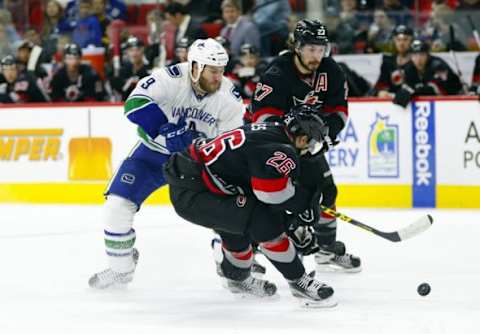 Jan 15, 2016; Raleigh, NC, USA; Carolina Hurricanes defensemen John-Michael Liles (26) stops Vancouver Canucks forward Brandon Prust (9) during the third period at PNC Arena. The Vancouver Canucks defeated the Carolina Hurricanes 3-2 in overtime. Mandatory Credit: James Guillory-USA TODAY Sports