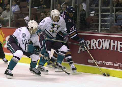 27 Oct 2000: Ruslan Salei #24 of the Anaheim Ducks and teammate Oleg Tverdovsky #10 smother Georges Laraque #27 of the Edmonton Oilers against the boards during the first period at the Pond in Anaheim, California. DIGITAL IMAGE. Mandatory Credit: Harry How/ALLSPORT