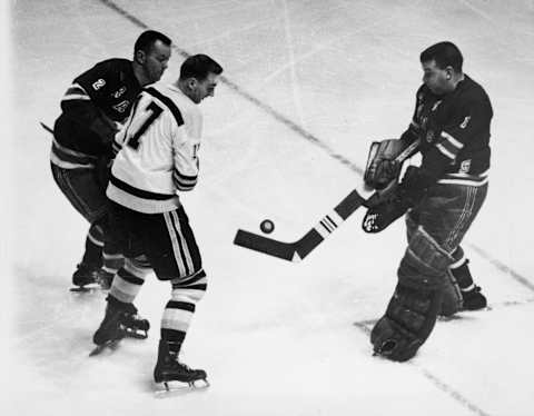 Canadian ice hockey player Lorne ‘Gump’ Worsley (1929 – 2007) (left), goalkeeper for the New York Rangers, in action on the ice during a game against the Boston Bruins at Madison Square Garden, New York, New York, December 3, 1961. Worsley’s teammate Doug Harvey (right) and the Bruins’ Don McKenney both keep their eyes on the puck. (Photo by Bruce Bennett Studios/Getty Images)