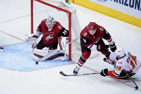 Feb 12, 2016; Glendale, AZ, USA; Calgary Flames center Matt Stajan (18) shoots on Arizona Coyotes goalie Louis Domingue (35) as defenseman Michael Stone (26) defends during the second period at Gila River Arena. Mandatory Credit: Matt Kartozian-USA TODAY Sports