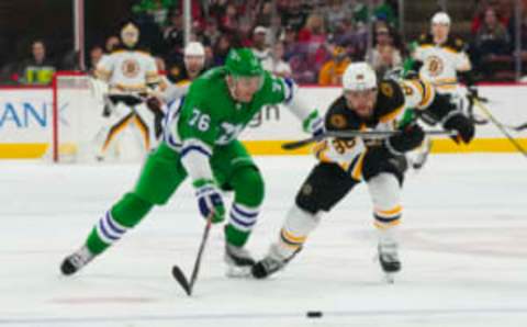 Mar 26, 2023; Raleigh, North Carolina, USA; Boston Bruins right wing David Pastrnak (88) and Carolina Hurricanes defenseman Brady Skjei (76) chase after the loose puck during the second period at PNC Arena. Mandatory Credit: James Guillory-USA TODAY Sports