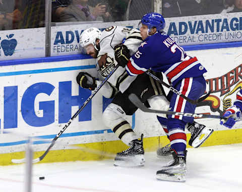 Amerks Jiri Kulich drives Hershey’s Garrett Pilon into the end boards.