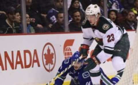 Nov 29, 2016; Vancouver, British Columbia, CAN; Minnesota Wild defenseman Gustav Olofsson (23) picks up the puck from Vancouver Canucks forward Alexandre Burrows (14) during the first period at Rogers Arena. Mandatory Credit: Anne-Marie Sorvin-USA TODAY Sports