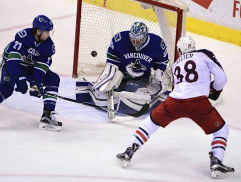 Feb 4, 2016; Vancouver, British Columbia, CAN; Columbus Blue Jackets forward Boone Jenner (38) shoots the puck against Vancouver Canucks goaltender Ryan Miller (30) and defenseman Ben Hutton (27) during the third period at Rogers Arena. The Blue Jackets won 2-1. Mandatory Credit: Anne-Marie Sorvin-USA TODAY Sports