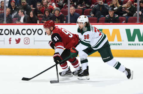 GLENDALE, ARIZONA – DECEMBER 19: Taylor Hall #91 of the Arizona Coyotes battles for a loose puck with Mats Zuccarello #36 of the Minnesota Wild at Gila River Arena on December 19, 2019, in Glendale, Arizona. (Photo by Norm Hall/NHLI via Getty Images)