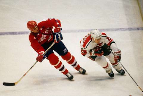 EAST RUTHERFORD, NJ – 1988: The New Jersey Devils’ left wing Perry Anderson #25 and the Washington Capitals’ defenceman Kevin Hatcher #4 skate near the boards during the Patrick Division Finals at the Meadowlands Arena circa 1987-88 season in East Rutherford, New Jersey. (Photo by Focus on Sport via Getty Images)