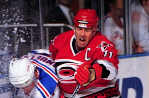 1997 Season: Carolina captain Kevin Dineen slams Ranger Ulf Samuelsson into the boards. (Photo by Bruce Bennett Studios via Getty Images Studios/Getty Images)