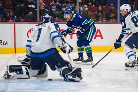 Nov 19, 2021; Vancouver, British Columbia, CAN; Vancouver Canucks forward Conor Garland (8) shoots through Winnipeg Jets goalie Eric Comrie (1) in the first period at Rogers Arena. Mandatory Credit: Bob Frid-USA TODAY Sports