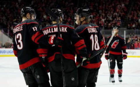 RALEIGH, NC – DECEMBER 31: Ryan Dzingel #18 of the Carolina Hurricanes scores an empty net goal and celebrates with teammates Lucas Wallmark #71 and Warren Foegele #13 during an NHL game against the Montreal Canadiens on December 31, 2019 at PNC Arena in Raleigh, North Carolina. (Photo by Gregg Forwerck/NHLI via Getty Images)