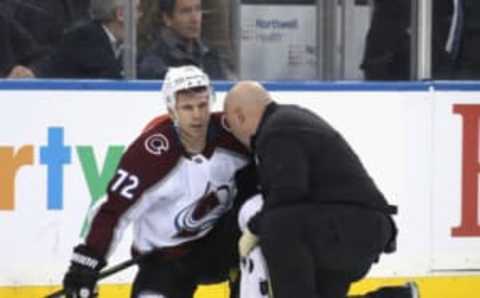 A trainer attends to Joonas Donskoi of the Avalanche following a check from Ryan Lindgren