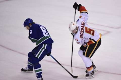 Oct 15, 2016; Vancouver, British Columbia, CAN; Vancouver Canucks defenseman Philip Larsen (63) reaches behind against Calgary Flames defenseman Mark Giordano (5) during the third period at Rogers Arena. The Vancouver Canucks won 2-1 in a shootout. Mandatory Credit: Anne-Marie Sorvin-USA TODAY Sports