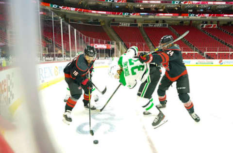 Jan 30, 2021; Raleigh, North Carolina, USA; Carolina Hurricanes defenseman Jake Bean (24) and Carolina Hurricanes center Vincent Trocheck (16) battle over the puck against Dallas Stars center Justin Dowling (37) PNC Arena. Mandatory Credit: James Guillory-USA TODAY Sports