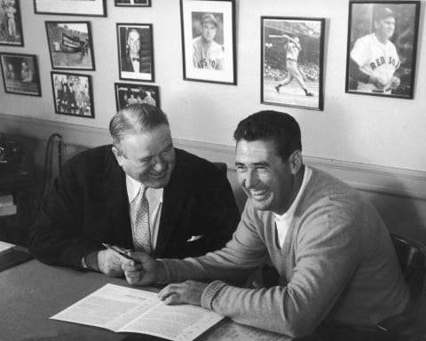 BOSTON – CIRCA 1955: (UNDATED FILE PHOTO) Baseball legend Ted Williams (1918 – 2002) of the Boston Red Sox (R) signs a baseball contract as Boston Manager Joe Cronin (1906 – 1984) looks on in 1958. The 83-year-old Williams, who was the last major league player to bat .400 when he hit .406 in 1941, died July 5, 2002 at Citrus County Memorial Hospital in Florida. He died of an apparent heart attack. (Photo by Getty Images)